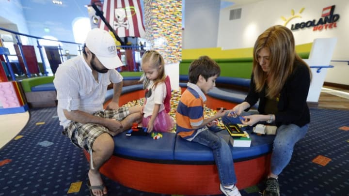 CARLSBAD, CA - SEPTEMBER 17: Tourists from Mexico, Diego, 6, and his sister Ximena, 3, Numata play with Lego toys with their mother Carolina Numata and their uncle Sergio Esqueda in the lobby area of North America's first ever Legoland Hotel at Legoland on September 17, 2013 in Carlsbad, California. The three-story, 250-room hotel is located at the entrance of Legoland California theme park. (Photo by Kevork Djansezian/Getty Images)