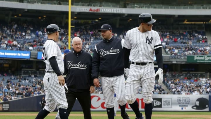 NEW YORK, NEW YORK - APRIL 20: Aaron Judge #99 of the New York Yankees is checked on by bench coach Josh Bard, trainer Steve Donohue and first base coach Reggie Willits #50 prior to leaving a game against the Kansas City Royals in the sixth inning at Yankee Stadium on April 20, 2019 in New York City. (Photo by Jim McIsaac/Getty Images)