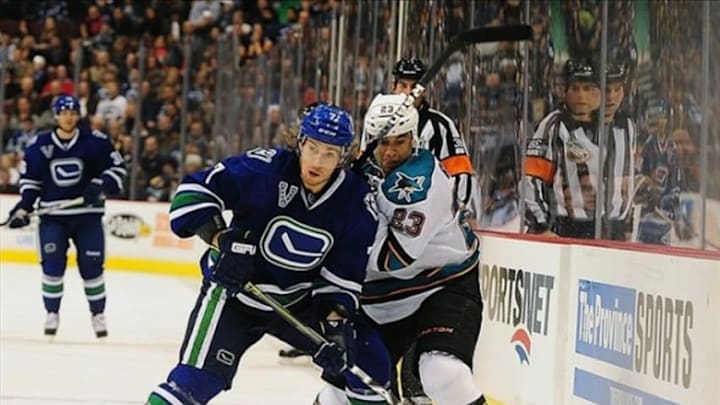 Mar 05, 2013; Vancouver, British Columbia, CANADA; Vancouver Canucks left wing David Booth (7) checks San Jose Sharks forward Scott Gomez (23) during the second period at Rogers Arena. Mandatory Credit: Anne-Marie Sorvin-USA TODAY Sports