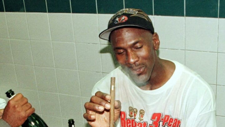 SALT LAKE CITY, UNITED STATES: Michael Jordan of the Chicago Bulls enjoys a cigar in the locker room 14 June 1998 after winning game six of the NBA Finals against the Utah Jazz at the Delta Center in Salt Lake City, UT. Jordan scored the winning basket to win the game 87-86 to win their sixth NBA Championship. Various reports 12 January say that Jordan plans to announce his retirement at a 13 January news conference in Chicago. (Photo credit should read MIKE NELSON/AFP via Getty Images)