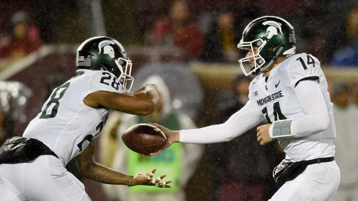 MINNEAPOLIS, MN – OCTOBER 14: Brian Lewerke #14 of the Michigan State Spartans hands the ball to teammate Madre London #28 against the Minnesota Golden Gophers during the first quarter of the game on October 14, 2017 at TCF Bank Stadium in Minneapolis, Minnesota. (Photo by Hannah Foslien/Getty Images)