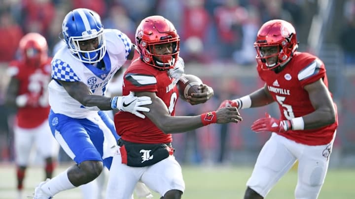 Nov 26, 2016; Louisville, KY, USA; Louisville Cardinals quarterback Lamar Jackson (8) tries to evade the tackle of Kentucky Wildcats cornerback J.D. Harmon (11) during the second half at Papa John