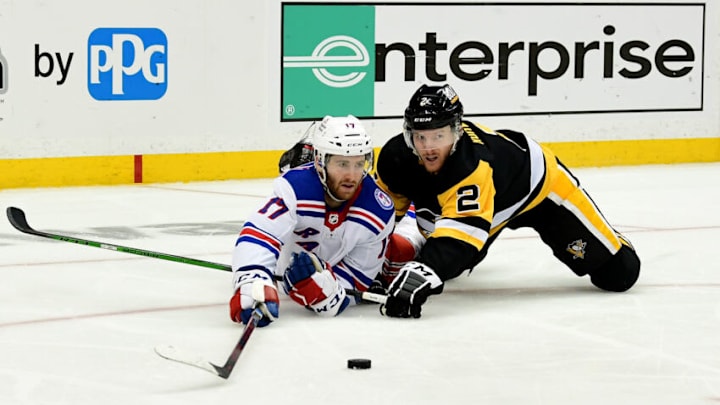 PITTSBURGH, PENNSYLVANIA - MAY 09: Kevin Rooney #17 of the New York Rangers and Chad Ruhwedel #2 of the Pittsburgh Penguins reach for the puck during the third period of Game Four of the First Round of the 2022 Stanley Cup Playoffs at PPG PAINTS Arena on May 09, 2022 in Pittsburgh, Pennsylvania. (Photo by Emilee Chinn/Getty Images)