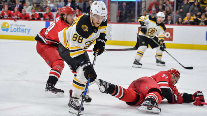 RALEIGH, NC - MARCH 13: Carolina Hurricanes Defenceman Justin Faulk (27) falls to the ice in front of a charging Boston Bruins Right Wing David Pastrnak (88) during a game between the Carolina Hurricanes and the Boston Bruins at the PNC Arena in Raleigh, NC on March 13, 2018. Boston defeated Carolina 6-4. (Photo by Greg Thompson/Icon Sportswire via Getty Images)