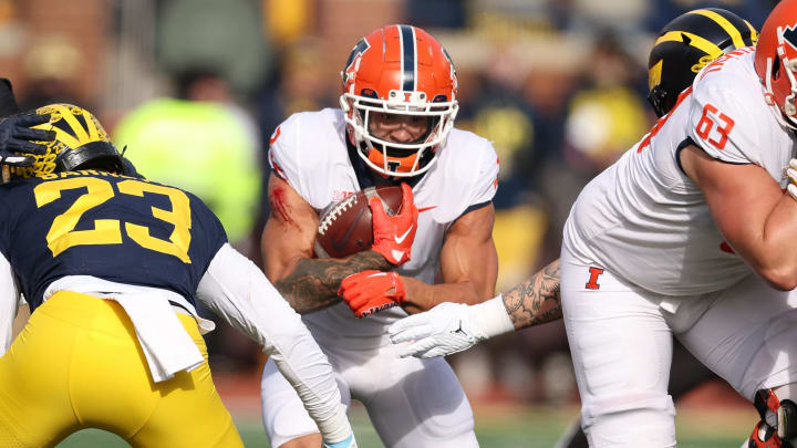 ANN ARBOR, MICHIGAN – NOVEMBER 19: Chase Brown #2 of the Illinois Fighting Illini looks for yards during a first half run next to Michael Barrett #23 of the Michigan Wolverines at Michigan Stadium on November 19, 2022 in Ann Arbor, Michigan. (Photo by Gregory Shamus/Getty Images)