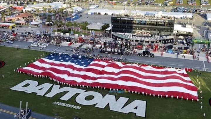 Jul 6, 2013; Daytona Beach, FL, USA; NASCAR Sprint Cup Series fans listen to the National Anthem as the U.S. flag is unveiled prior to the start of the Coke Zero 400 at Daytona International Speedway. Mandatory Credit: John David Mercer-USA TODAY Sports