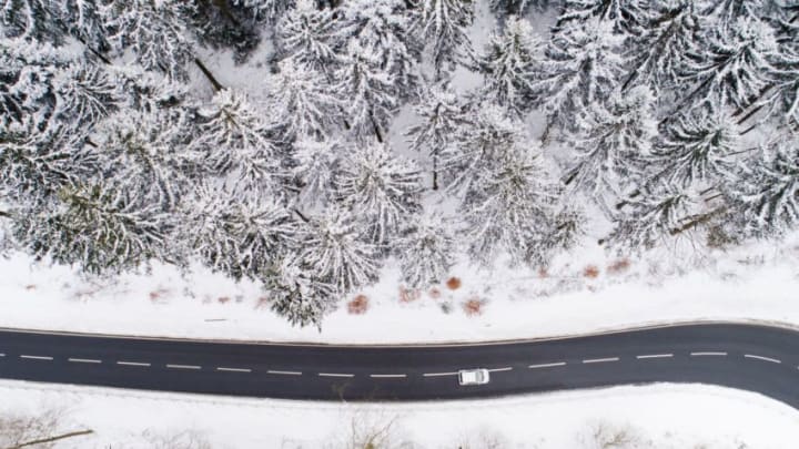This aerial view taken on February 26, 2018 with a drone shows a car driving on a country road through a winter snowy forest in the district of Holzminden, Germany.A wintry blast of freezing temperatures sweeps across Europe, with a biting wind from Siberia. The "Beast from the East", as the phenomenon has been dubbed by the British media, is expected to bring cold air from Russia over the next few days that will make it feel even chillier than thermometers indicate. / AFP PHOTO / dpa / Julian Stratenschulte / Germany OUT (Photo credit should read JULIAN STRATENSCHULTE/DPA/AFP via Getty Images)