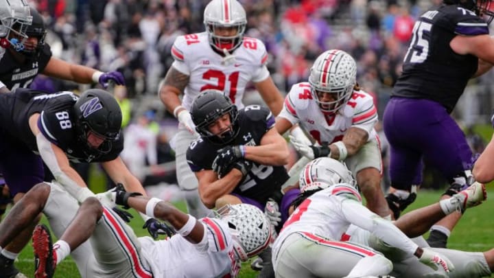 Nov 5, 2022; Evanston, Illinois, USA; Ohio State Buckeyes defensive end Javontae Jean-Baptiste (8), cornerback Denzel Burke (10) anbd safety Ronnie Hickman (14) tackle sNorthwestern Wildcats running back Evan Hull (26) during the second half of the NCAA football game at Ryan Field. Ohio State won 21-7. Mandatory Credit: Adam Cairns-The Columbus DispatchNcaa Football Ohio State Buckeyes At Northwestern Wildcats