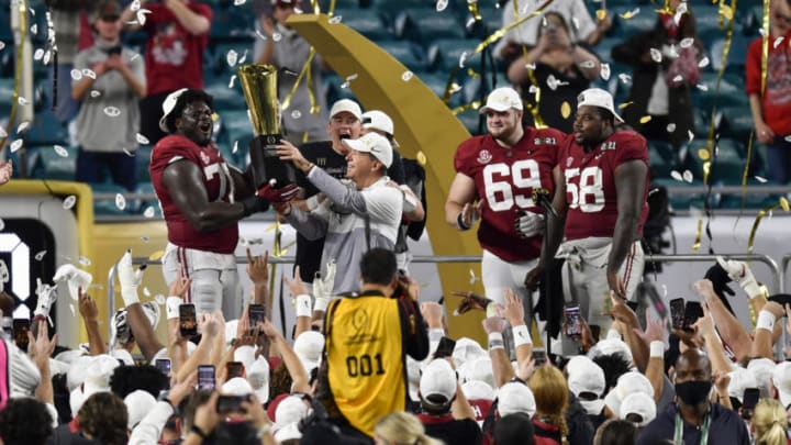 MIAMI GARDENS, FLORIDA - JANUARY 11: Head coach Nick Saban and Alex Leatherwood #70 of the Alabama Crimson Tide hold up the CFP National Championship Trophy on the trophy presentation stage with Mac Jones #10, Landon Dickerson #69, Christian Barmore #58, and DeVonta Smith #6 after the College Football Playoff National Championship football game against the Ohio State Buckeyes at Hard Rock Stadium on January 11, 2021 in Miami Gardens, Florida. The Alabama Crimson Tide defeated the Ohio State Buckeyes 52-24. (Photo by Alika Jenner/Getty Images)