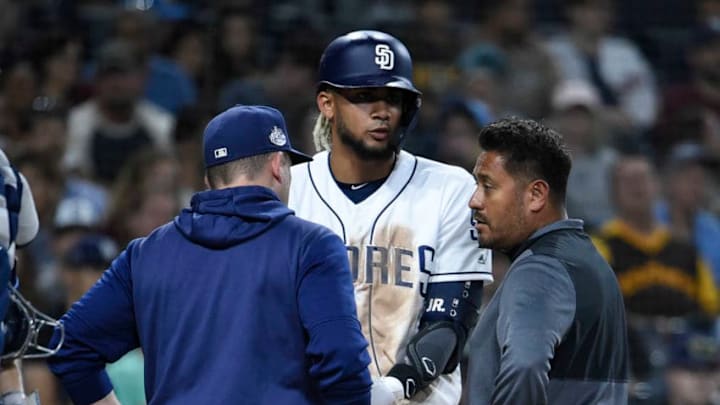 SAN DIEGO, CA - AUGUST 13: Andy Green #14 of the San Diego Padres and a trainer talk with Fernando Tatis Jr. #23 during the sixth inning of a baseball game against the Tampa Bay Rays at Petco Park August 13, 2019 in San Diego, California. (Photo by Denis Poroy/Getty Images)