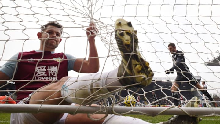 Burnley's English defender James Tarkowski (L) reacts as he slides into the net while attempting but failing to block the shot from Burnley's English striker Ashley Barnes (unseen) when Barnes scored the opening goal as Leicester City's English striker Jamie Vardy (R) celebrates the goal during the English Premier League football match between Burnley and Leicester City at Turf Moor in Burnley, north west England on January 19, 2020. (Photo by Oli SCARFF / AFP) / RESTRICTED TO EDITORIAL USE. No use with unauthorized audio, video, data, fixture lists, club/league logos or 'live' services. Online in-match use limited to 120 images. An additional 40 images may be used in extra time. No video emulation. Social media in-match use limited to 120 images. An additional 40 images may be used in extra time. No use in betting publications, games or single club/league/player publications. / (Photo by OLI SCARFF/AFP via Getty Images)