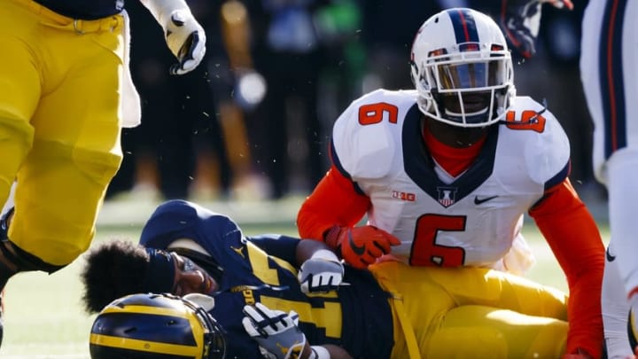 Oct 22, 2016; Ann Arbor, MI, USA; Michigan Wolverines running back Chris Evans (12) loose his helmet after he is tackled by Illinois Fighting Illini defensive lineman Carroll Phillips (6) in the first half at Michigan Stadium. Mandatory Credit: Rick Osentoski-USA TODAY Sports