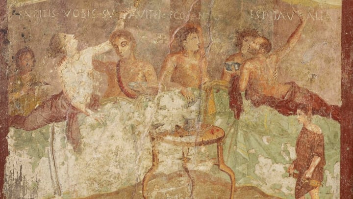 A fresco wall panel showing a dinner party with painted message