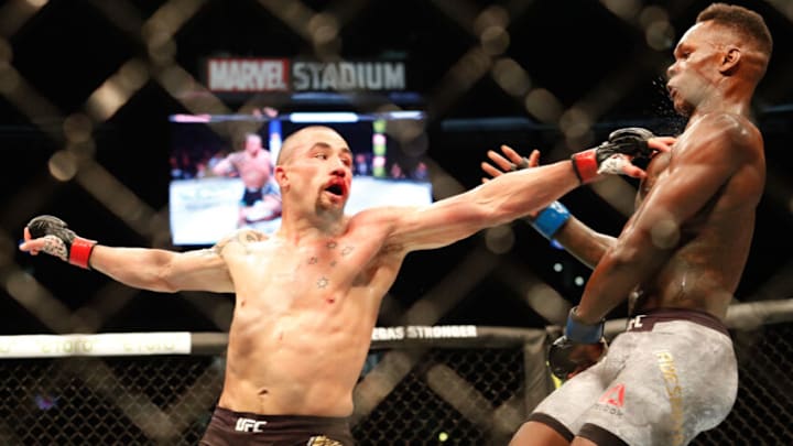 Robert Whittaker of Australia (L) punches Israel Adesanya of New Zealand (R) during the middleweight title bout of the UFC 243 fight night in Melbourne on October 6, 2019. (Photo by ASANKA BRENDON RATNAYAKE / AFP) / -- IMAGE RESTRICTED TO EDITORIAL USE - STRICTLY NO COMMERCIAL USE -- (Photo by ASANKA BRENDON RATNAYAKE/AFP via Getty Images)