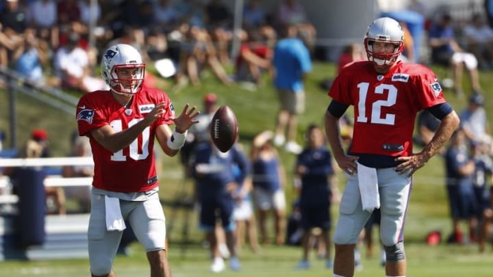 Jul 30, 2016; Foxborough, MA, USA; New England Patriots quarterback Tom Brady (12) looks on as quarterback Jimmy Garoppolo (10) takes a snap during training camp at Gillette Stadium. Mandatory Credit: Winslow Townson-USA TODAY Sports