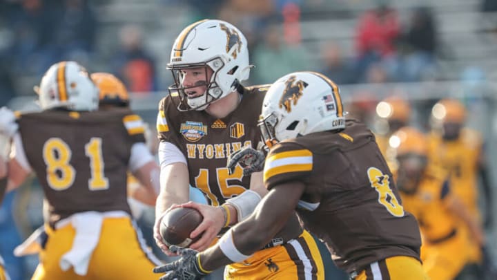 BOISE, ID - DECEMBER 21: Quarterback Levi Williams #15 hands the ball to running back Titus Swen of the Wyoming Cowboys during first half action against the Kent State Golden Flashes at the Famous Idaho Potato Bowl on December 21, 2021 at Albertsons Stadium in Boise, Idaho. (Photo by Loren Orr/Getty Images)