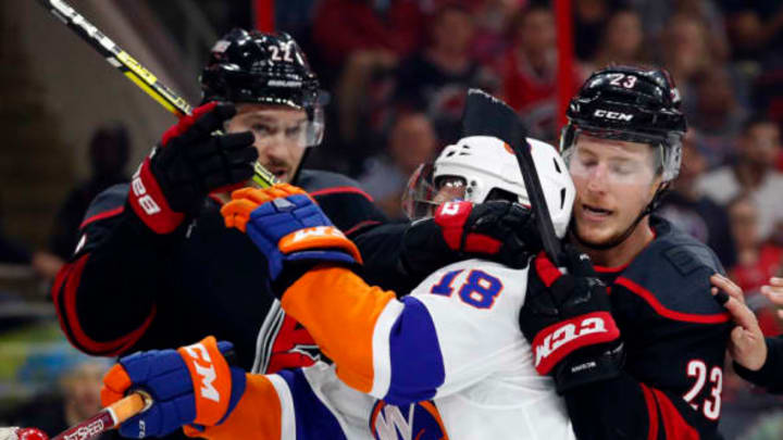 RALEIGH, NC – May 1: Brett Pesce #22 and Brock McGinn #23 of the Carolina Hurricanes tie up Anthony Beauvillier #18 of the New York Islanders in Game Three of the Eastern Conference Second Round during the 2019 NHL Stanley Cup Playoffs at PNC Arena on May 1, 2019, in Raleigh, North Carolina. (Photo by Karl DeBlaker/NHLI via Getty Images)