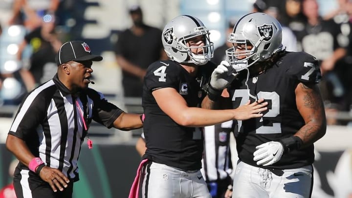 Oct 23, 2016; Jacksonville, FL, USA; Oakland Raiders quarterback Derek Carr (4) holds back Oakland Raiders tackle Donald Penn (72) as umpire Shawn Smith (14) approaches during the second half of a football game against the Jacksonville Jaguars at EverBank Field. The Raiders won 33-16. Mandatory Credit: Reinhold Matay-USA TODAY Sports