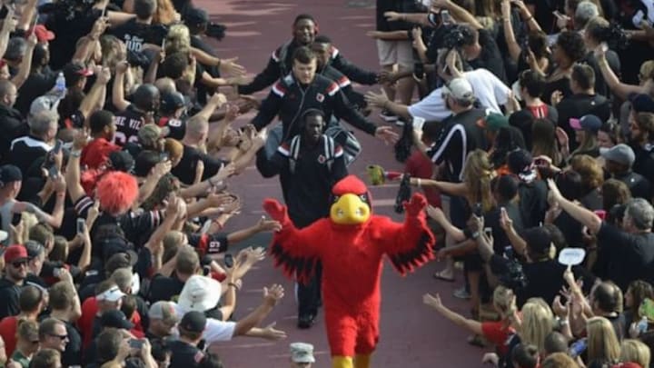 Sep 1, 2014; Louisville, KY, USA; The Louisville Cardinals mascot Louie leads the players through the crowd during the Card March prior to their game against the Miami Hurricanes at Papa John