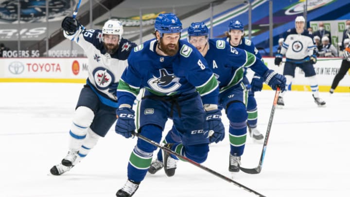 VANCOUVER, BC - MARCH 22: Jordie Benn #8 of the Vancouver Canucks, Mathieu Perreault #85 of the Winnipeg Jets and Tyler Myers #57 of the Vancouver Canucks chase after a loose puck during NHL action at Rogers Arena on March 22, 2021 in Vancouver, Canada. (Photo by Rich Lam/Getty Images)