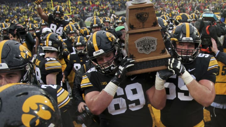 IOWA CITY, IOWA- NOVEMBER 23: Offensive linemen Keegan Render #69 and Ross Reynolds #59 of the Iowa Hawkeyes carry the Heroes Trophy off the field after their match-up against the Nebraska Cornhuskers on November 23, 2018 at Kinnick Stadium, in Iowa City, Iowa. (Photo by Matthew Holst/Getty Images)