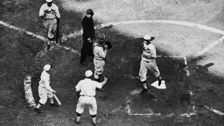 American baseball player infielder Andy High (1897 – 1981) of the St. Louis Cardinals (third from left) raises a hand to greet teammate outfielder George Watkins (1900 – 1970) as he comes across home plate after hitting a home run during game seven of the 1931 World Series against the Philadelphia Athletics, Sportsman’s Park IV, St. Louis, October 10, 1931. The Cardinals won the game 4-2 to take the series. (Photo by Hulton Archive/Getty Images)