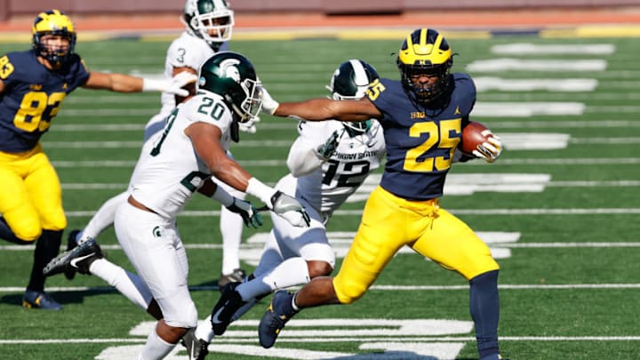 Oct 31, 2020; Ann Arbor, Michigan, USA; Michigan Wolverines running back Hassan Haskins (25) stiff arms Michigan State Spartans safety Emmanuel Flowers (20) in the first half at Michigan Stadium. Mandatory Credit: Rick Osentoski-USA TODAY Sports