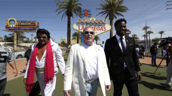LAS VEGAS, NEVADA - APRIL 25: An Elvis Presley impersonator (L) walks by Las Vegas Raiders owner Mark Davis (C) and former Las Vegas Raiders player Marcel Reese during a kick-off event celebrating the 2022 NFL Draft by turning the Welcome To Fabulous Las Vegas sign silver and black on April 25, 2022 in Las Vegas, Nevada. (Photo by David Becker/Getty Images)