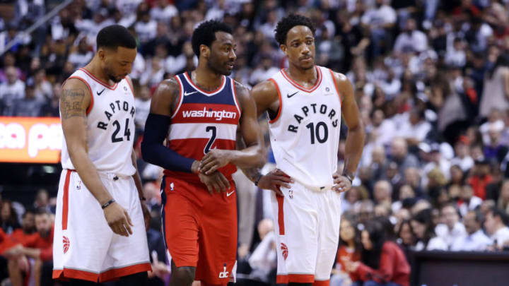 LTORONTO, ON - APRIL 25: Norman Powell #24 and DeMar DeRozan #10 of the Toronto Raptors talk with John Wall #2 of the Washington Wizards during the second half of Game Five in Round One of the 2018 NBA playoffs at Air Canada Centre on April 25, 2018 in Toronto, Canada. NOTE TO USER: User expressly acknowledges and agrees that, by downloading and or using this photograph, User is consenting to the terms and conditions of the Getty Images License Agreement. (Photo by Vaughn Ridley/Getty Images)