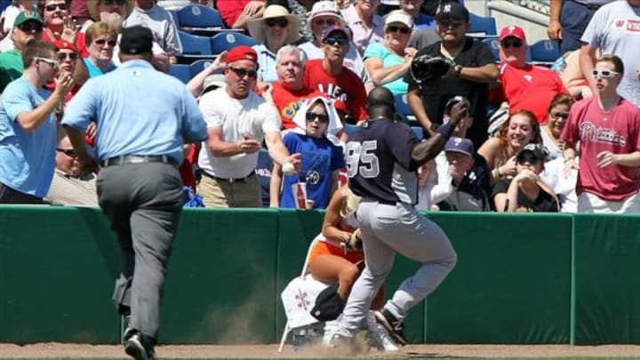 March 19, 2013; Clearwater, FL, USA; New York Yankees second baseman Ronnier Mustelier (95) goes after the foul ball as a hooters ball girl gets in the way during the fourth inning against the Philadelphia Phillies at Bright House Networks Field. Mandatory Credit: Kim Klement-USA TODAY Sports
