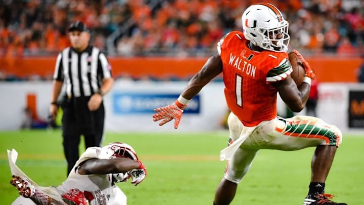 Sep 10, 2016; Miami Gardens, FL, USA; Miami Hurricanes running back Mark Walton (1) eludes Florida Atlantic Owls defensive back Andrew Soroh (14) during the second half at Hard Rock Stadium. Miami won 38-10. Mandatory Credit: Steve Mitchell-USA TODAY Sports