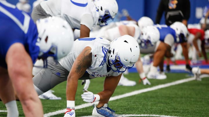 Kansas players go through stretching routines Tuesday morning during practice at the Kansas Indoor Practice Facility.