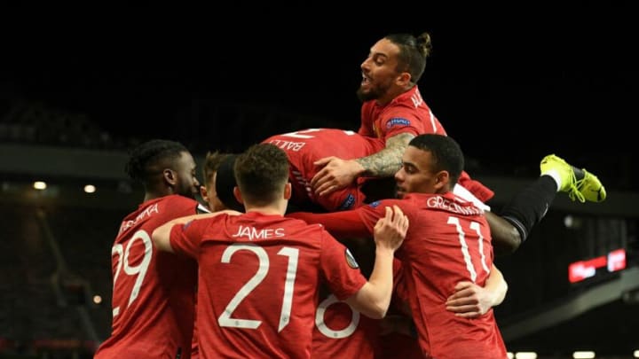 Manchester United's Brazilian defender Alex Telles (top R) jumps in to celebrate the opening goal scored by Manchester United's Ivorian midfielder Amad Diallo (obscured) during the UEFA Europa League round of 16 first leg football match between Manchester United and AC Milan at Old Trafford in Manchester, north west England, on March 11, 2021. (Photo by Oli SCARFF / AFP) (Photo by OLI SCARFF/AFP via Getty Images)
