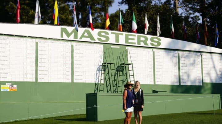 Apr 7, 2021; Augusta, Georgia, USA; Patrons pose for a photo in front of the main leaderboard during a practice round for The Masters golf tournament at Augusta National Golf Club. Mandatory Credit: Rob Schumacher-USA TODAY Sports