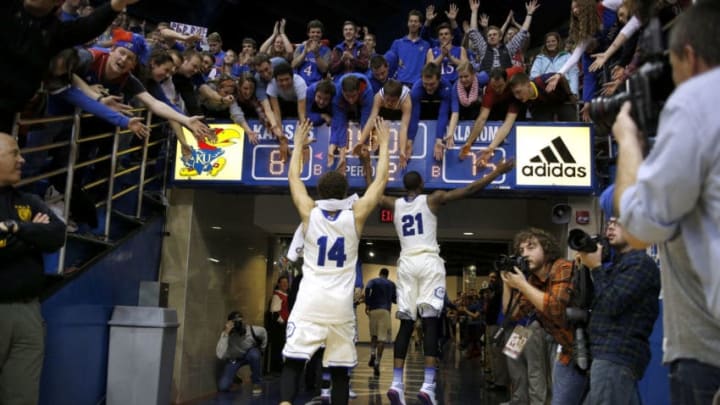 LAWRENCE, KS - FEBRUARY 24: Brannen Greene #14 and Joel Embiid #21 of the Kansas Jayhawks celebrate with fans after an 83-75 win over the Oklahoma Sooners at Allen Fieldhouse on February 24, 2014 in Lawrence, Kansas. (Photo by Ed Zurga/Getty Images)