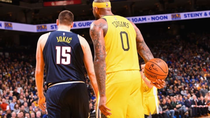 OAKLAND, CA - MARCH 8: Nikola Jokic #15 of the Denver Nuggets and DeMarcus Cousins #0 of the Golden State Warriors look on during the game on March 8, 2019 at ORACLE Arena in Oakland, California. NOTE TO USER: User expressly acknowledges and agrees that, by downloading and or using this photograph, user is consenting to the terms and conditions of Getty Images License Agreement. Mandatory Copyright Notice: Copyright 2019 NBAE (Photo by Noah Graham/NBAE via Getty Images)