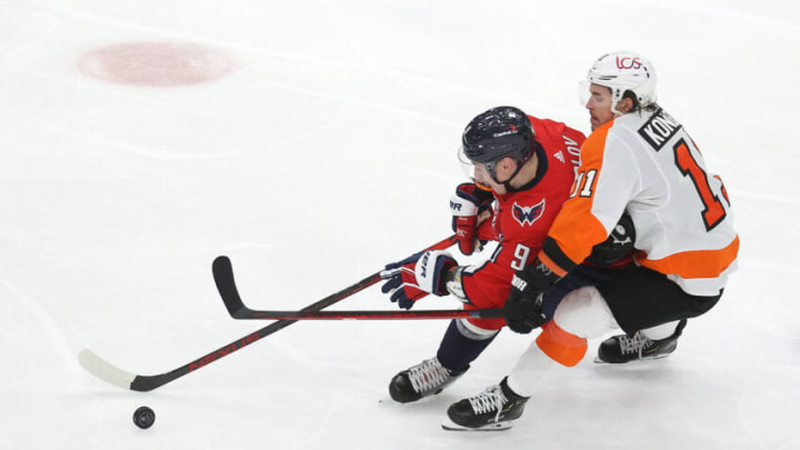 WASHINGTON, DC - MAY 07: Dmitry Orlov #9 of the Washington Capitals and Travis Konecny #11 of the Philadelphia Flyers go after the puck at Capital One Arena on May 07, 2021 in Washington, DC. (Photo by Rob Carr/Getty Images)