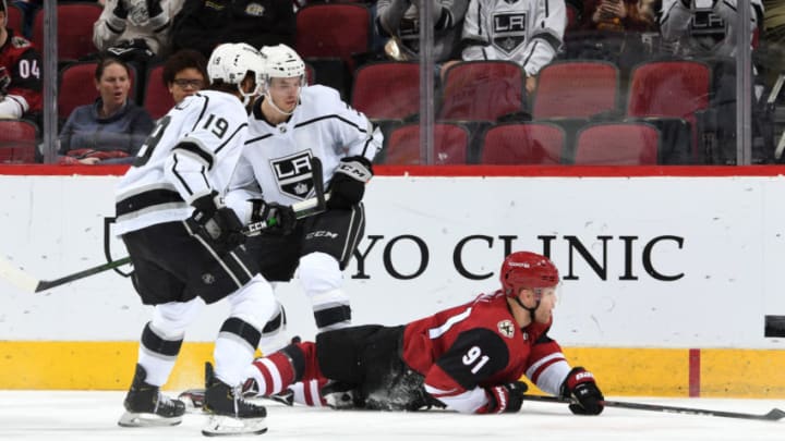 GLENDALE, ARIZONA - JANUARY 30: Taylor Hall #91 of the Arizona Coyotes falls to the ice as he plays the puck between Alex Iafallo #19 and Matt Roy #3 of the Los Angeles Kings during the second period of the NHL hockey game at Gila River Arena on January 30, 2020 in Glendale, Arizona. (Photo by Norm Hall/NHLI via Getty Images)
