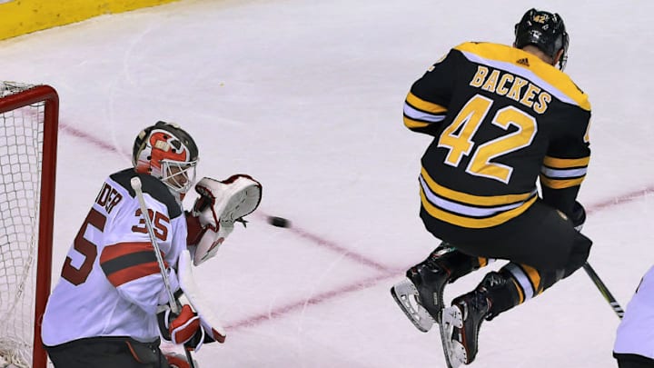 BOSTON - JANUARY 23: Boston Bruins' David Backes (42) leaps in front of Devils goalie Cory Schneider as a Boston teammate shoots the puck on net. Schneider kept his eye on the puck and made a glove save. The Boston Bruins host the New Jersey Devils in a regular season NHL hockey game at TD Garden in Boston on Jan. 23, 2018. (Photo by Jim Davis/The Boston Globe via Getty Images)