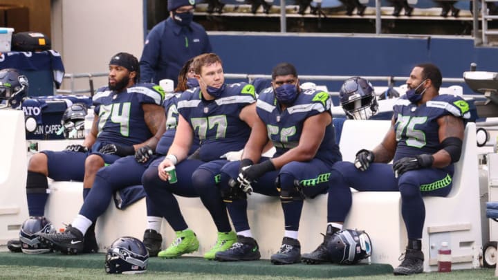 SEATTLE, WASHINGTON - DECEMBER 27: (L-R) Cedric Ogbuehi #74, Ethan Pocic #77, Jordan Simmons #66 and Duane Brown #76 of the Seattle Seahawks react from the sidelines in the second quarter against the Los Angeles Rams at Lumen Field on December 27, 2020 in Seattle, Washington. (Photo by Abbie Parr/Getty Images)