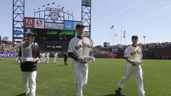 April 13, 2015 San Francisco, USA; San Francisco Giants pitcher Tim Lincecum (left) manager Bruce Bochy (center) and catcher Buster Posey (right) carry the World Series trophies from the 2010, 2012 and 2014 seasons before a baseball game against the Colorado Rockies at AT&T Park. Mandatory Credit: Jeff Chiu-Pool Photo via USA TODAY Sports