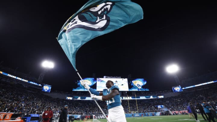 JACKSONVILLE, FLORIDA - JANUARY 14: Shaquille Quarterman #50 waves a Jacksonville Jaguars flag after defeating the Los Angeles Chargers at TIAA Bank Field on January 14, 2023 in Jacksonville, Florida. (Photo by Douglas P. DeFelice/Getty Images)