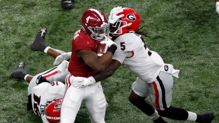 Alabama Crimson Tide running back Brian Robinson Jr. (4) stiff arms Georgia Bulldogs defensive back Kelee Ringo (5) as he rushes the ball Monday, Jan. 10, 2022, during the College Football Playoff National Championship at Lucas Oil Stadium in Indianapolis.