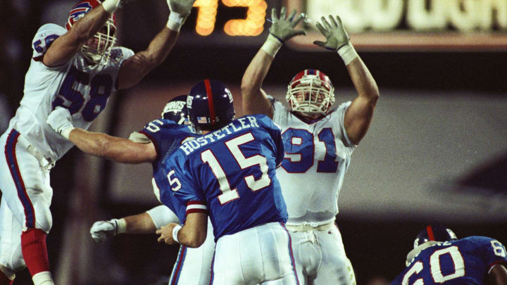 Jan 27, 1991; Tampa, FL, USA; FILE PHOTO; New York Giants quarterback Jeff Hostetler (15) throws the ball while center Bart Oates (65) and guard Eric Moore (60) block Buffalo Bills linebacker Shane Conlan (58) and nose tackle Jeff Wright (91) during Super Bowl XXV at Tampa Stadium. The Giants defeated the Bills 19-20. Mandatory Credit: USA TODAY Sports