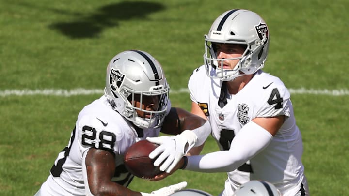 KANSAS CITY, MISSOURI – OCTOBER 11: Derek Carr #4 of the Las Vegas Raiders hands the ball off to Josh Jacobs #28 against the Kansas City Chiefs during the first quarter at Arrowhead Stadium on October 11, 2020, in Kansas City, Missouri. (Photo by Jamie Squire/Getty Images)