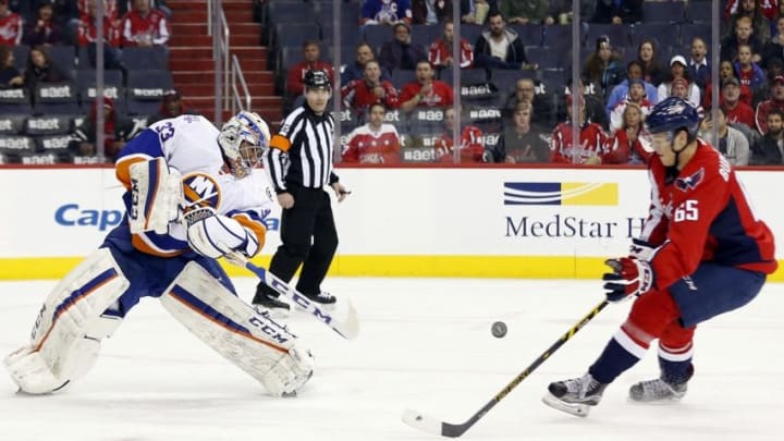 Apr 5, 2016; Washington, DC, USA; New York Islanders goalie Christopher Gibson (33) clears the puck from Washington Capitals left wing Andre Burakovsky (65) in the first period at Verizon Center. The Islanders won 4-3 in overtime. Mandatory Credit: Geoff Burke-USA TODAY Sports