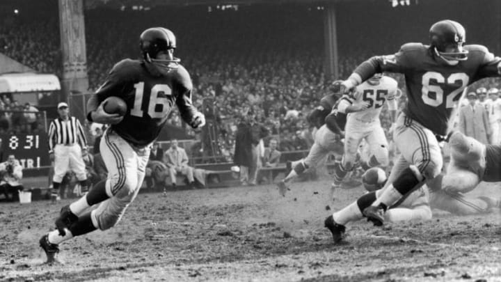 New York Giants football player Frank Gifford (#16) runs with protection from teammate Darrell Dess (#62) during a game against the Philadelphia Eagles, 1960s. (Photo by Robert Riger/Getty Images)