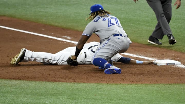 ST PETERSBURG, FLORIDA - JULY 24: Manuel Margot #13 of the Tampa Bay Rays slides safely under the glove of Vladimir Guerrero Jr. #27 of the Toronto Blue Jays on a throw over from Rafael Dolis #41 (not pictured) during the eighth inning on Opening Day at Tropicana Field on July 24, 2020 in St Petersburg, Florida. The 2020 season had been postponed since March due to the COVID-19 pandemic. (Photo by Douglas P. DeFelice/Getty Images)