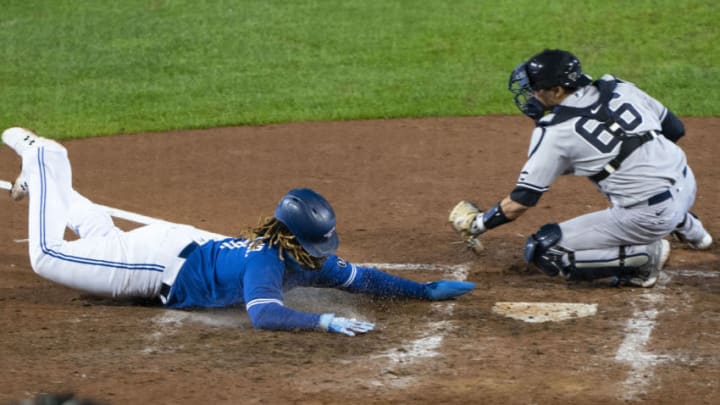 Sep 24, 2020; Buffalo, New York, USA; Toronto Blue Jays first baseman Vladimir Guerrero Jr. (27) dives into home plate ahead of the tag by New York Yankees catcher Kyle Higashioka (66) to score a run during the sixth inning at Sahlen Field. Mandatory Credit: Gregory Fisher-USA TODAY Sports