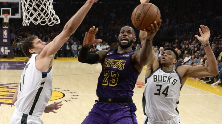 LeBron James #23 of the Los Angeles Lakers scores a basket as he drives in between Giannis Antetokounmpo #34 and Brook Lopez #11 of the Milwaukee Bucks